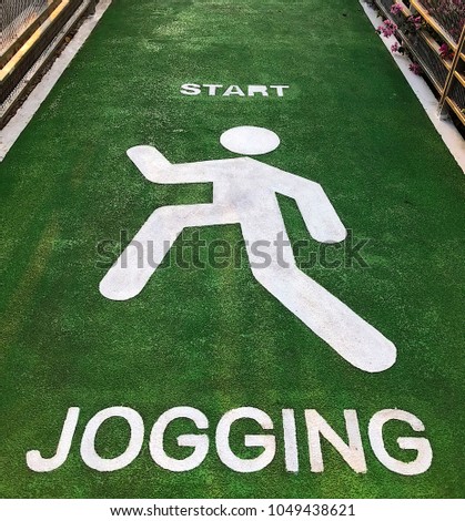 Jogging sign on green lane beside city road for running and exercise activity