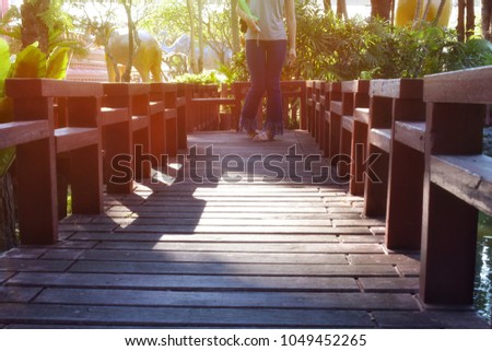 A woman stands on a wooden bridge surrounded by trees.