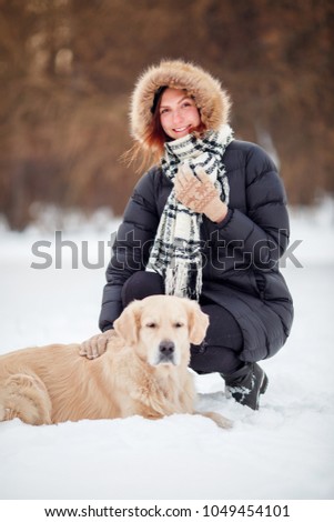 Image of happy woman in scarf sitting next to labrador at winter