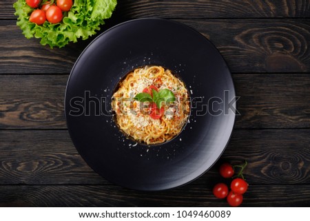 Spaghetti bolognese on black plate.