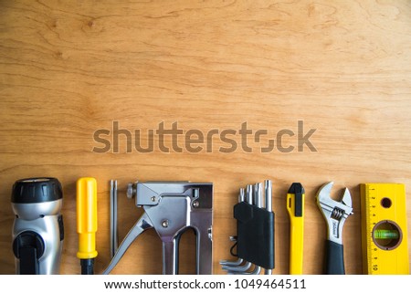 A set of tools: stapler, lantern, screwdriver, keys, cutter, level, ruler on a wooden background. Place for text