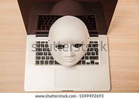 Conceptual photo, mask on a laptop as a symbol of a hacker attack, view from above