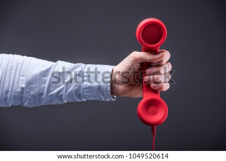 Businessman holds a red telephone with a stretched arm
