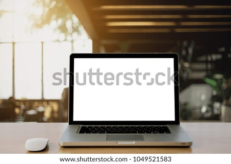 Laptop with blank screen and wireless mouse on Empty space wooden desk at office Interior blurred background of light bokeh.