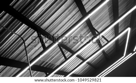 Black and white of neon lighting decoration under modern ceiling metal frame. Neon light bulb linear type illuminated background