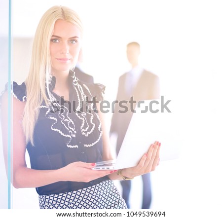 Young businesswoman holding a laptop, standing on office