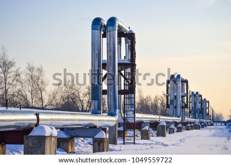 Overground heat pipes. Pipeline above ground, conducting heat for heating the city. Winter. Snow. Royalty-Free Stock Photo #1049559722
