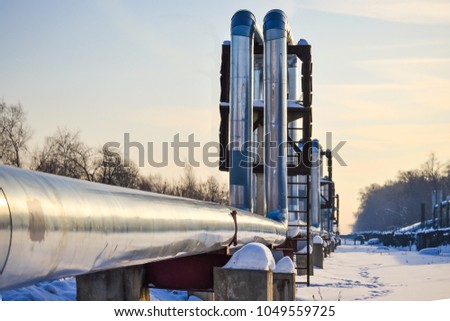 Overground heat pipes. Pipeline above ground, conducting heat for heating the city. Winter. Snow. Royalty-Free Stock Photo #1049559725