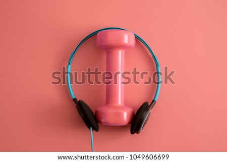 Styled stock photography of dumbbell with head phone on pink background. Flat lay.