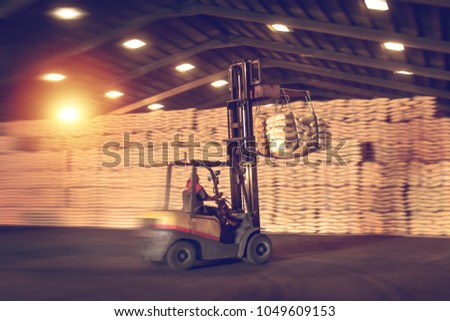 Speeding forklift handling sugar bags from container into warehouse. Distribution, Logistics Import Export, Warehouse operation concept. Royalty-Free Stock Photo #1049609153
