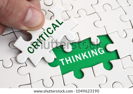 The human hand fills the last missing elements of the surface from the jigsaw puzzle. Image with words critical and thinking Royalty-Free Stock Photo #1049623190