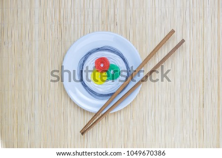 Sushi roll made of colorful threads on plate with chopsticks isolated on bamboo mat background minimal flat lay creative concept