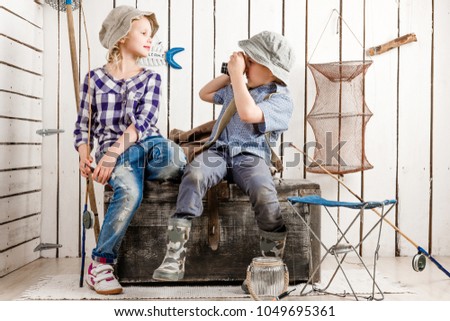little boy taking picture of cute little girl sitting on big old chest