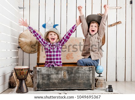 two little laughing children with hands up sitting in big old chest