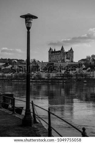 A black and white picture of the Castle of Saumur taken from the other side of the river.