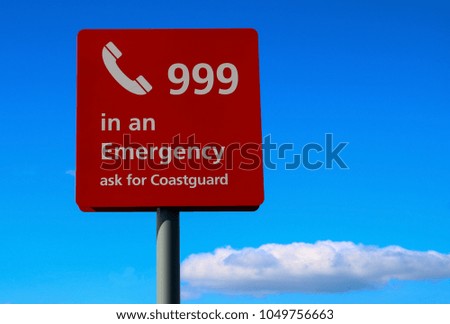 Red emergency sign at a coastal beach location