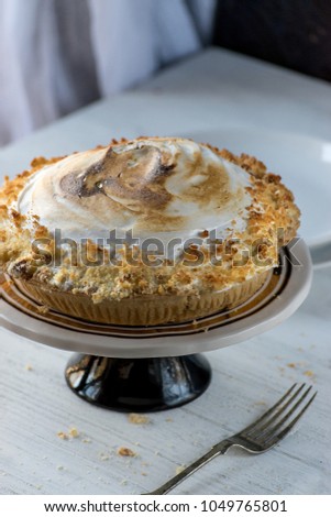 lemon meringue pie on white table with fork and crumbs