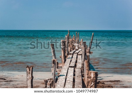 Perspective view of an old wooden pier on a large sea bay with a blue sky in the background