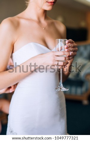 bride in a white dress in hands holds a glass