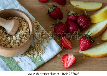 
picture of granola, red strawberry and sliced ??apples