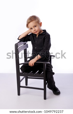 Portrait of five years old boy dressed in black on white background. Studio shot