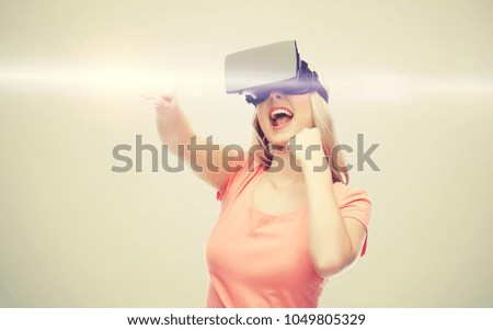 3d technology, virtual reality, entertainment and people concept - happy young woman with virtual reality headset or 3d glasses playing game and fighting over gray background and laser light