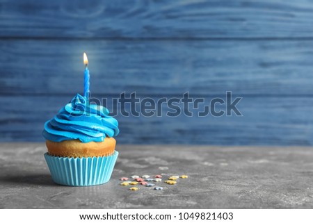 Delicious birthday cupcake with burning candle on table