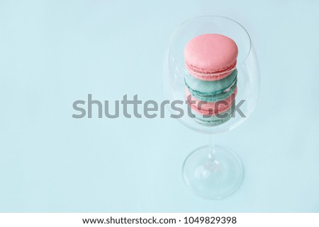 pink and mint macaroons lie in a glass transparent glass that stands on a mint background
