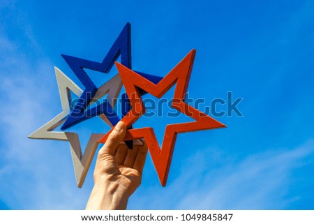 Woman hand holding white, blue and red star against blue sky