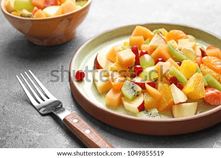 Plate with fresh cut fruits on table