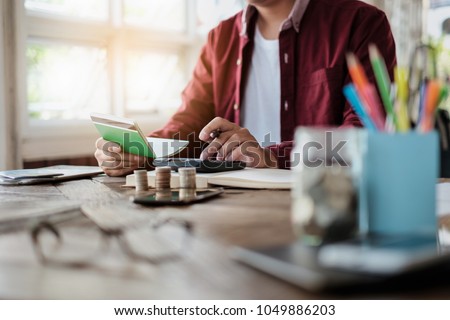 Business man hands holding saving account passbook with calculator, account and saving concept. Royalty-Free Stock Photo #1049886203