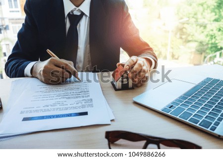 Confident man in suit and tie holding pen and sign in insurance document. insurance concept.
