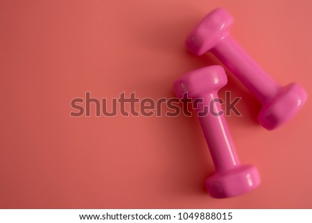 Styled stock photography of fitness equipment dumbbells notepad pencil and earphone on pink background. Flat lay.