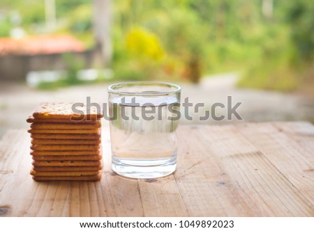 Biscuit crackers and a glass of drinking water on wooden table.
