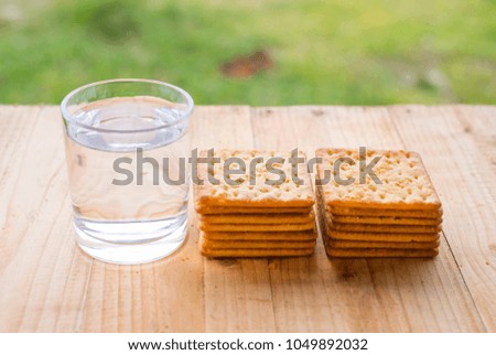 Biscuit crackers and a glass of drinking water on wooden table.