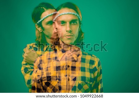 Studio shot of rebellious young man wearing yellow checkered shirt against green background