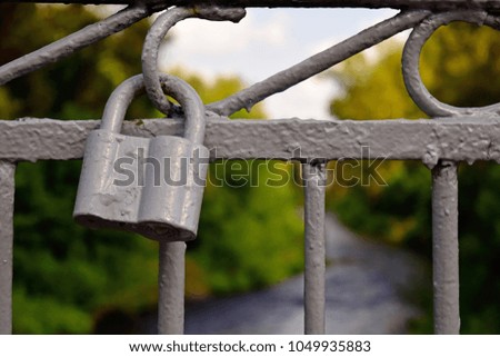 A gray old lock on a metal fence.