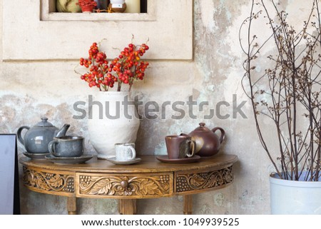 Still life details, cup of tea and cup of coffee on outdoor retro vintage wooden coffee table shelf decorated with red flowers and dry flowers .