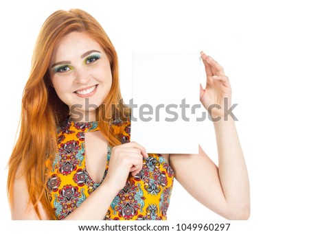 Woman stands with a rectangle in vertical in hands. Blank space for text. Fashion and colorful makeup. Redhead teenager wears vibrant yellow dress and floral patterns. White background.