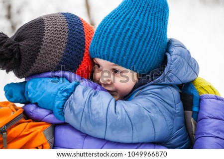 The kid hugs Mom. A boy and his mother are walking in the winter forest. A child kisses his mother. The woman supports her son. Motherhood.
