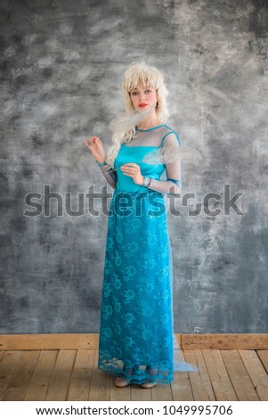 Young blonde girl in a long blue dress, symbolizing the winter. Carnival, costume show. Cold heart. Animator, dancer, actor. Colorful picture for poster or advertisement.