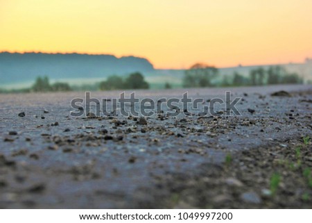 Early morning, roadside. Pebbles on the road close up. Road in the background of the forest. Clear sky at sunrise