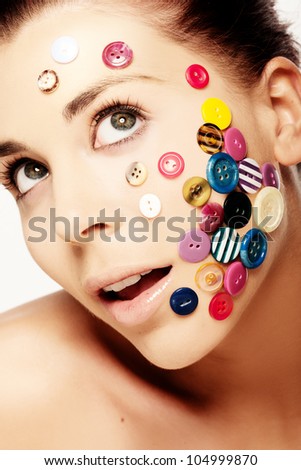 Close up portrait of beautiful woman with various colorful buttons on her face
