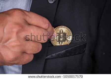 close up business man in suit pick bitcoin in to pocket
