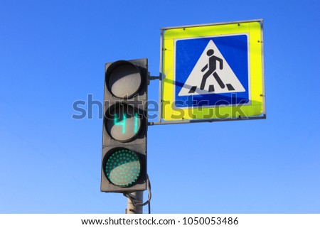 Green Traffic Light with Timer and Pedestrian Crosswalk Stop Sign on Empty Blue Sky Background. City Street Traffic Light Showing 41 Seconds to Cross Street. Walk Caution, Safety and Warning Concept.