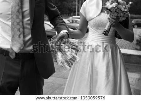 Black and white wedding picture: bridegroom holding champagne glasses and bride taking his hand