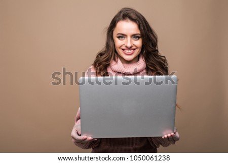 Young happy smiling woman in casual clothes holding laptop and sending email to her best friend