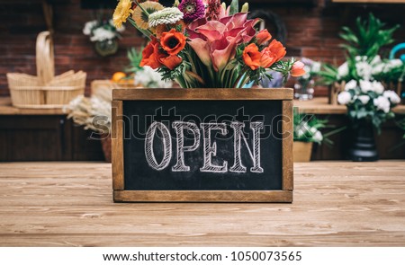Open sign on wooden table among flowers bouquet
