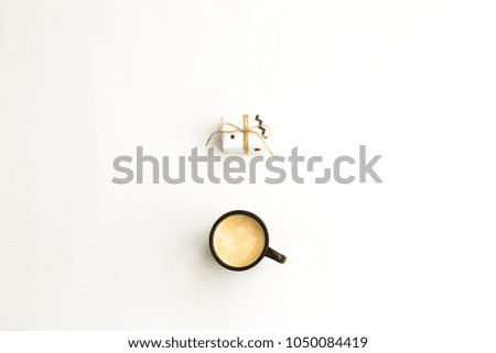 A cup of coffee and one small minimalist gift on a white background. Flat lay, top view