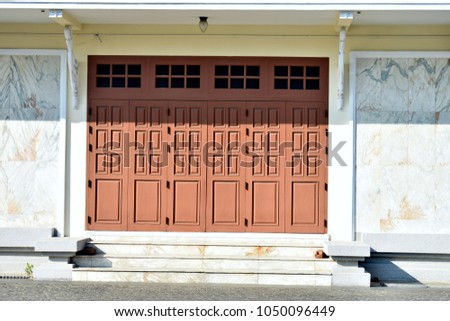 Brown wood door is the entrance of the multi-purpose room The walls of the building are made of marble, with applied art traditional Thai art.
